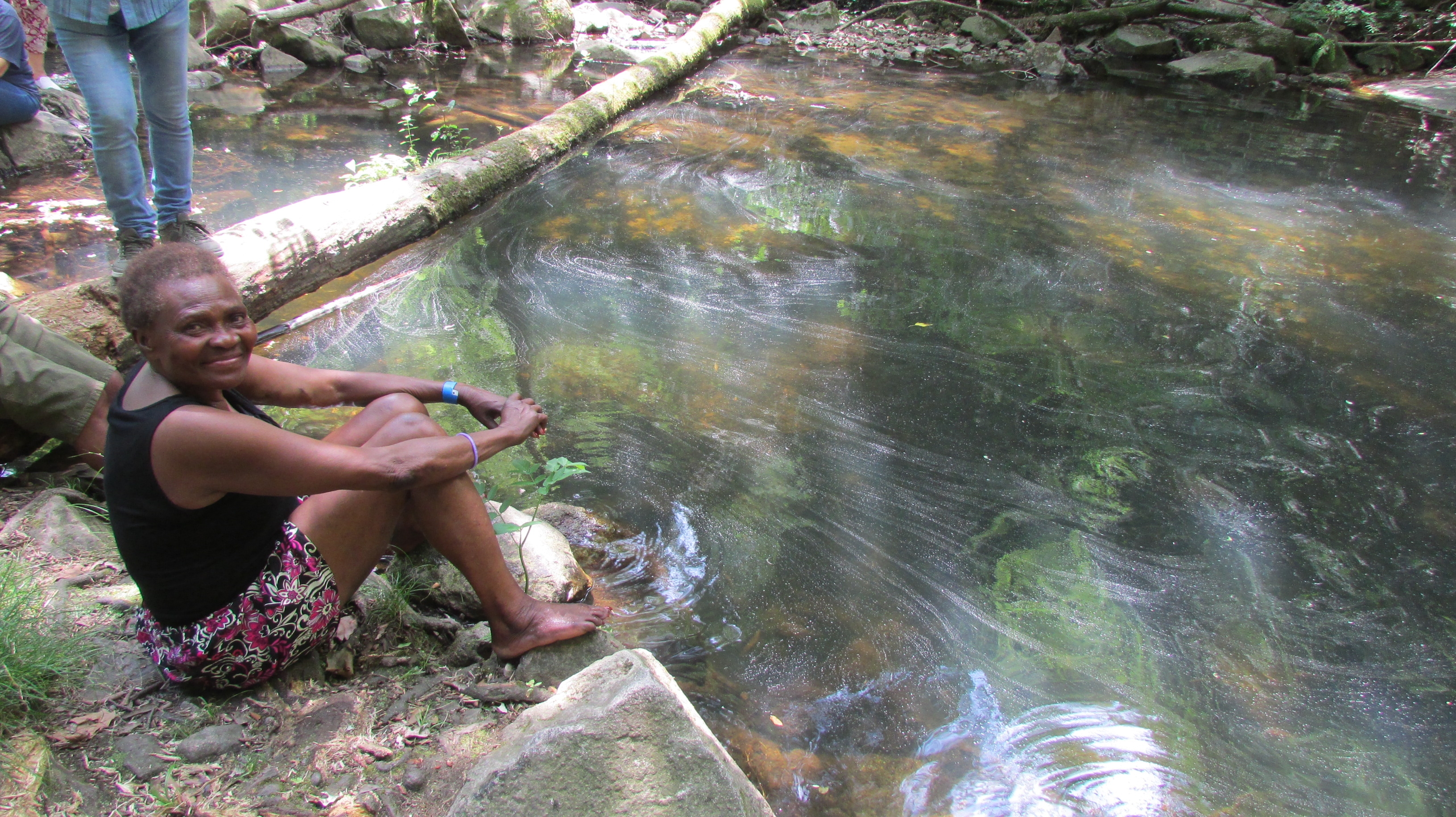Una de las usuarias de Llar de Pau descansa junto al río en una salida organizada
